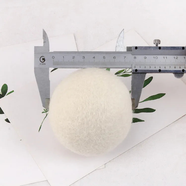 A wool drying ball for laundry next to a plain cotton storage bag on a background.