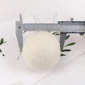 A wool drying ball for laundry next to a plain cotton storage bag on a background.