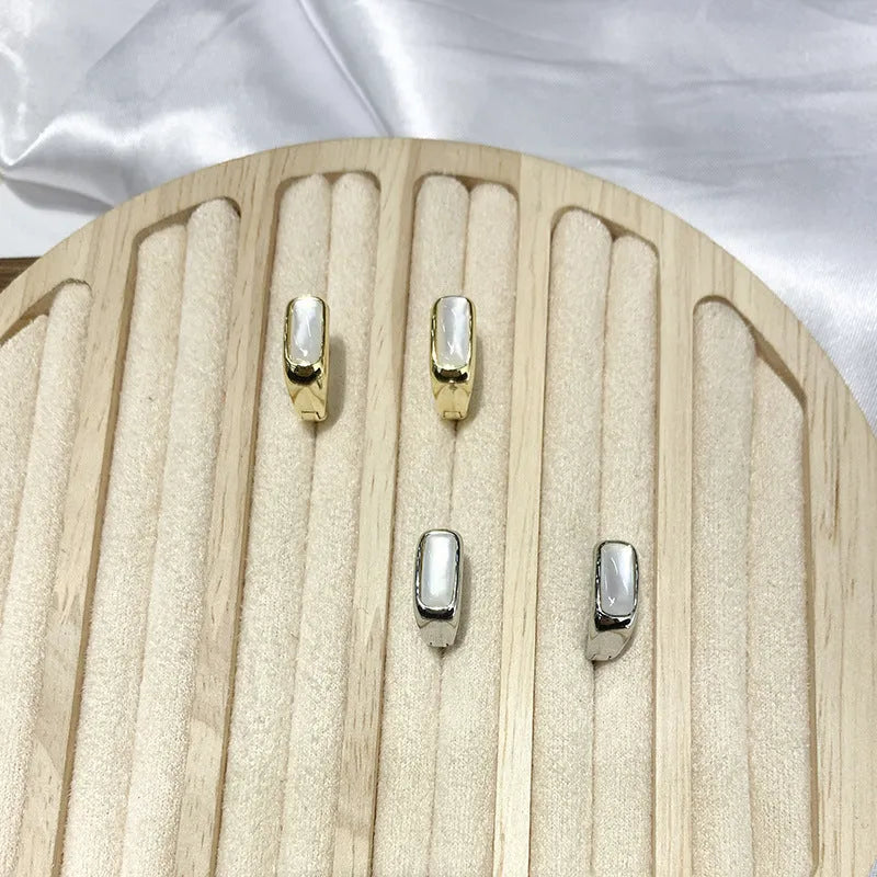 Four pairs of round buckle earrings in gold and silver metal finish on white background