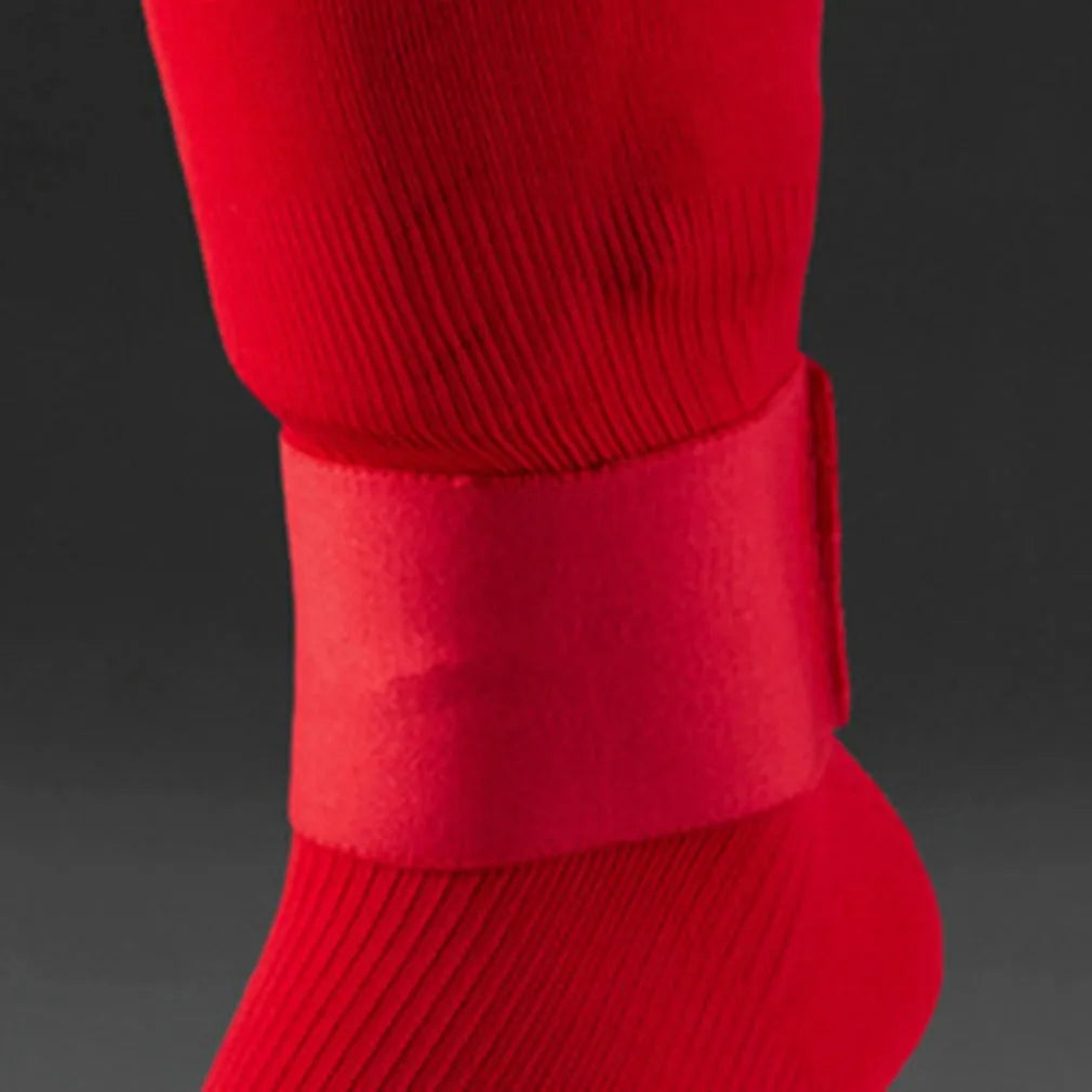 Adjustable red rubber football shin guard belt strap securing a shin pad