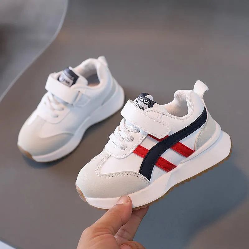 Children's white synthetic leather sneakers with Velcro fastening and textured rubber sole.