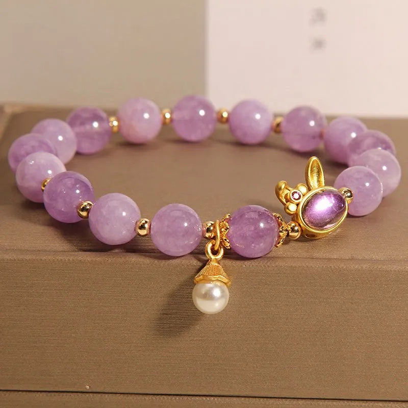 Mauve jade rabbit bracelet with a purplish red jade hare head charm on a crystal band.