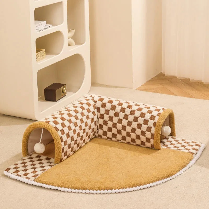 Brown plaid collapsible cat tunnel bed with central mat on a wooden floor.