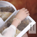Women's freshwater pearl bracelet with fan-shaped design on a wrist, showing elastic and chain fastening options.