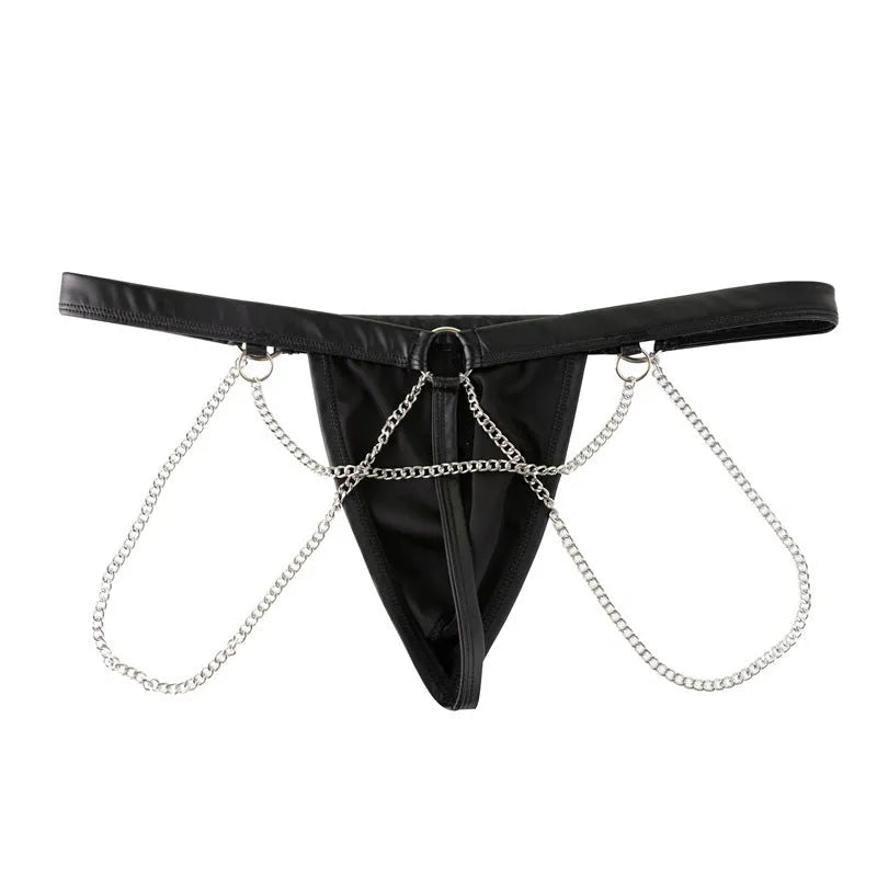 Black men's patent leather thong underwear with metal chain decoration on a grey background.
