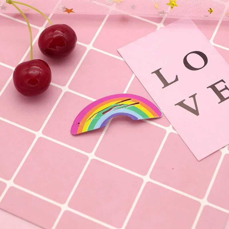 Close-up of a children's metal barrette with a colourful painted strawberry print and baking varnish finish.