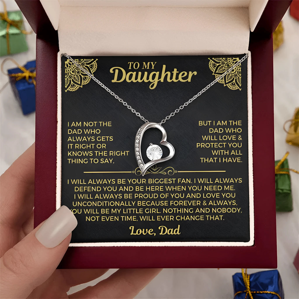 A hollow heart-shaped pendant necklace in a gold or silver finish, presented inside a gift box with a greeting card.