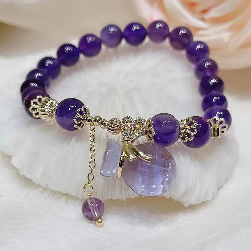 Purple crystal bracelet with geometric shapes, money bag pendant and peace buckle on wrist