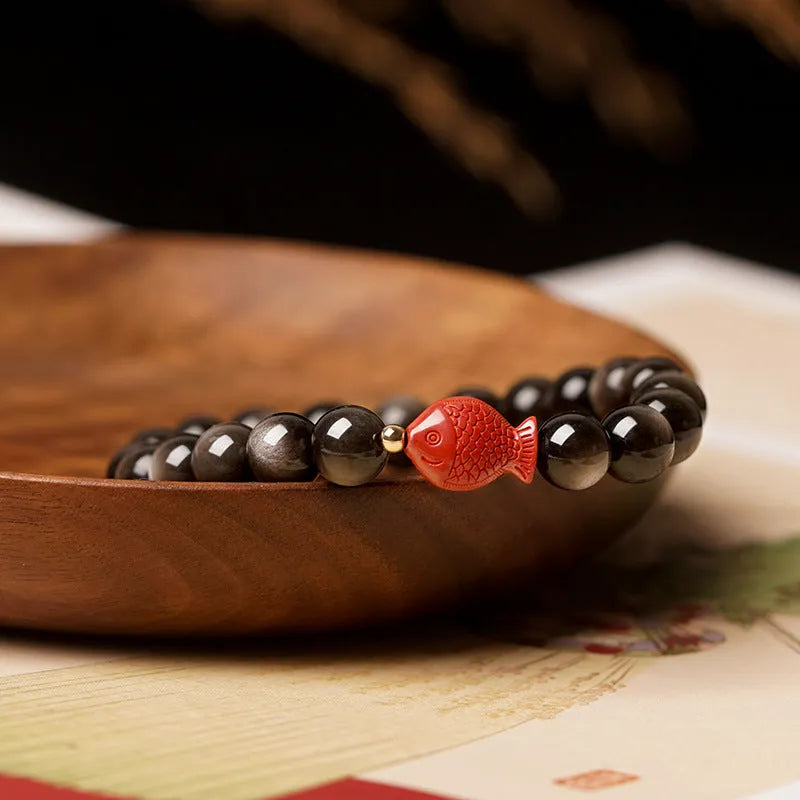 Natural obsidian bracelet with round beads and red cinnabar fungus decoration on wrist