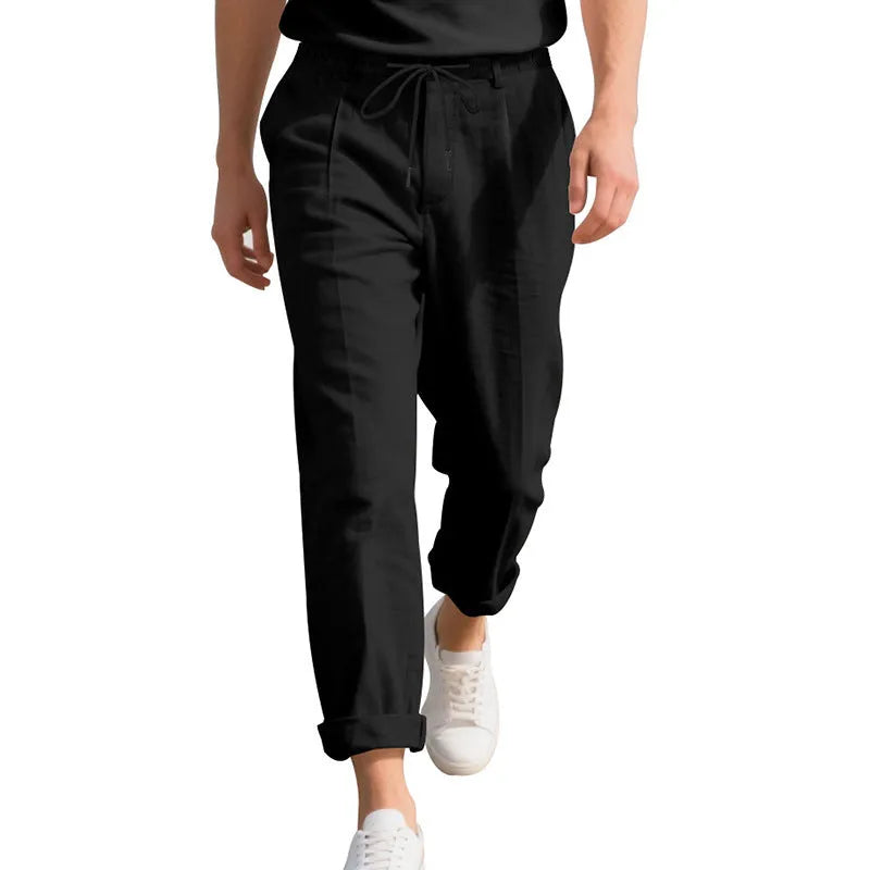 Men's light beige linen trousers with drawstring waist and straight-leg design laid flat