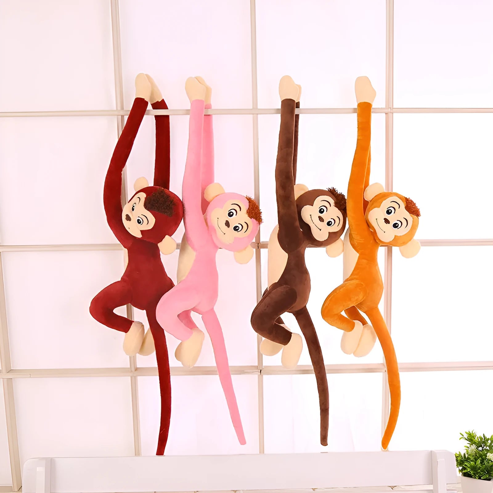 Long arm hanging monkey plush toy decoration in pink colour draped over curtain pole