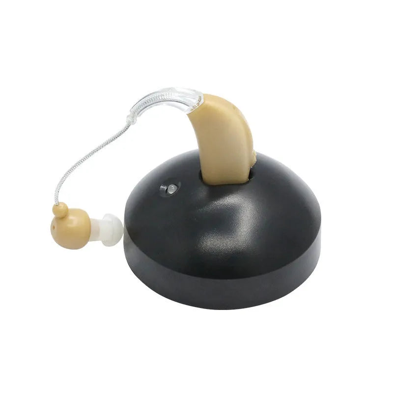 Black silicone rechargeable hearing aid amplifier with charging cable on a plain surface.