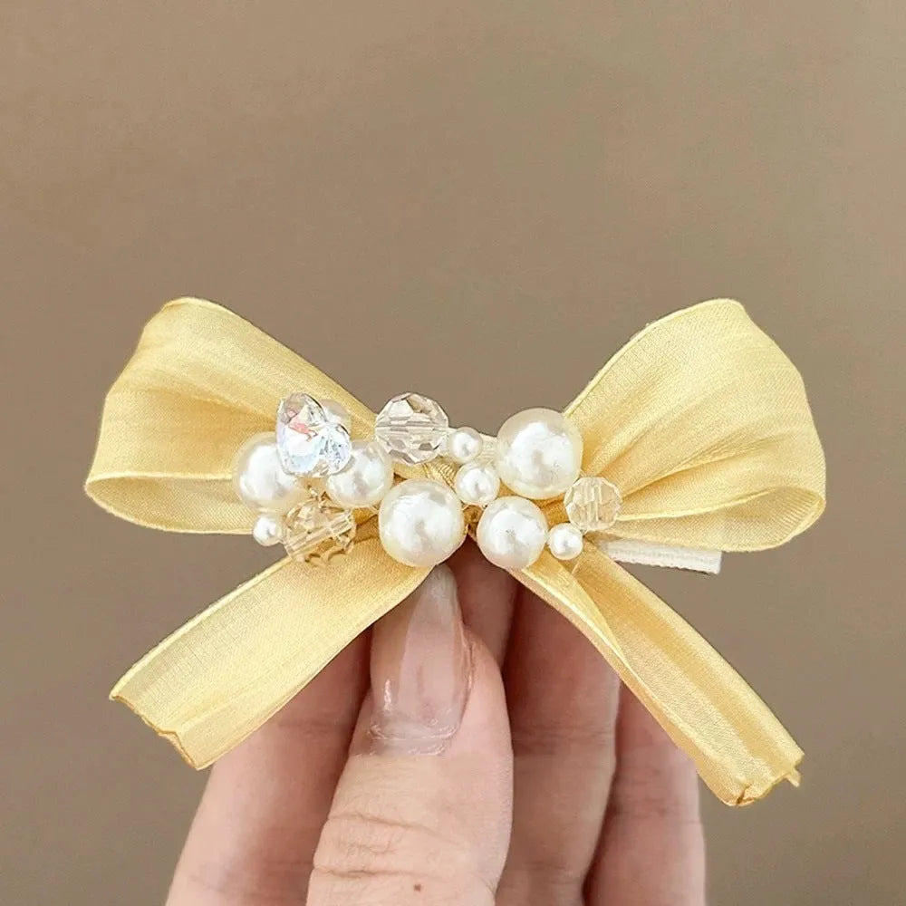 Yellow cloth bow barrette with rhinestone and pearl accents on duckbill hair clip