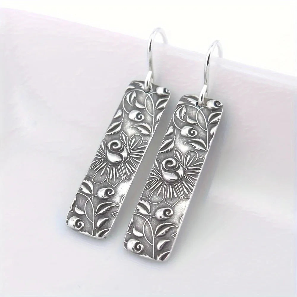 Silver-coloured long geometric drop earrings with carved vine patterns
