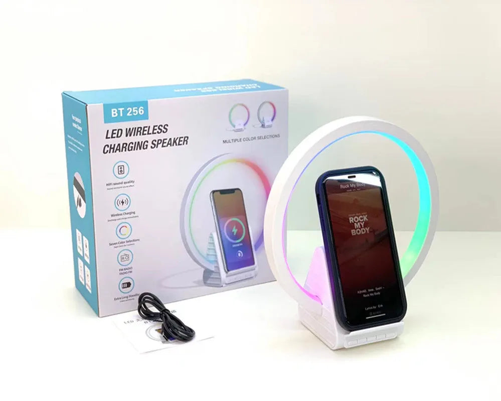 White smart Bluetooth speaker with integrated wireless charging pad and ambience light on a desk.