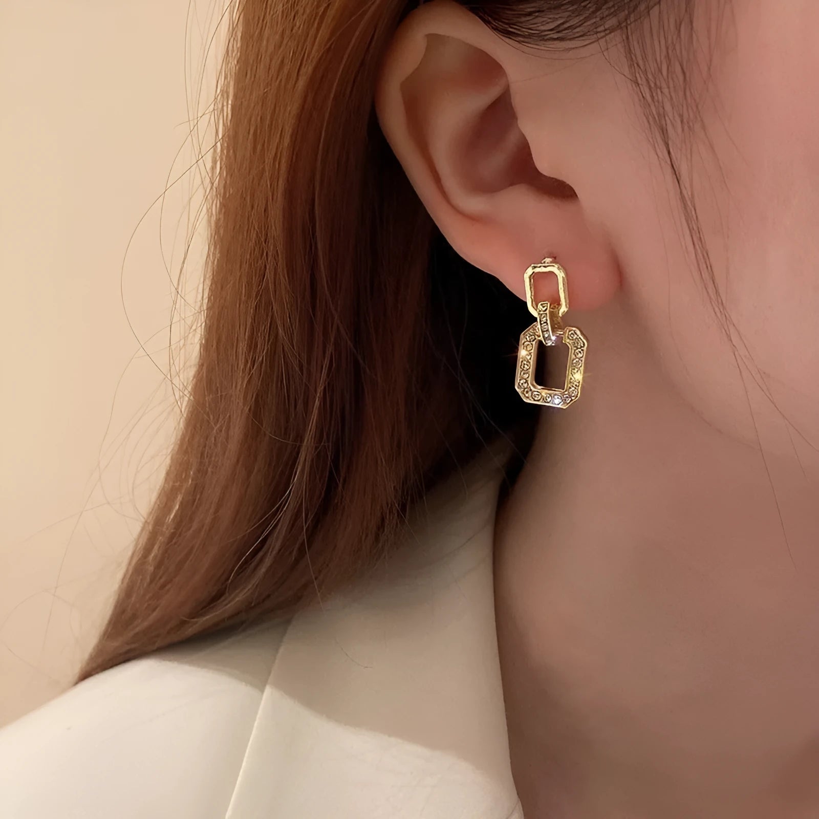Pair of geometric alloy ear studs with electroplated finish on white background