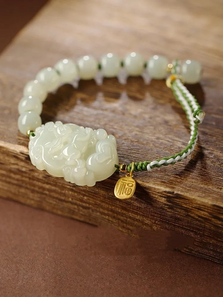 Hetian jade Rabbit charm bracelet on a red rope with a small silver blessing card.
