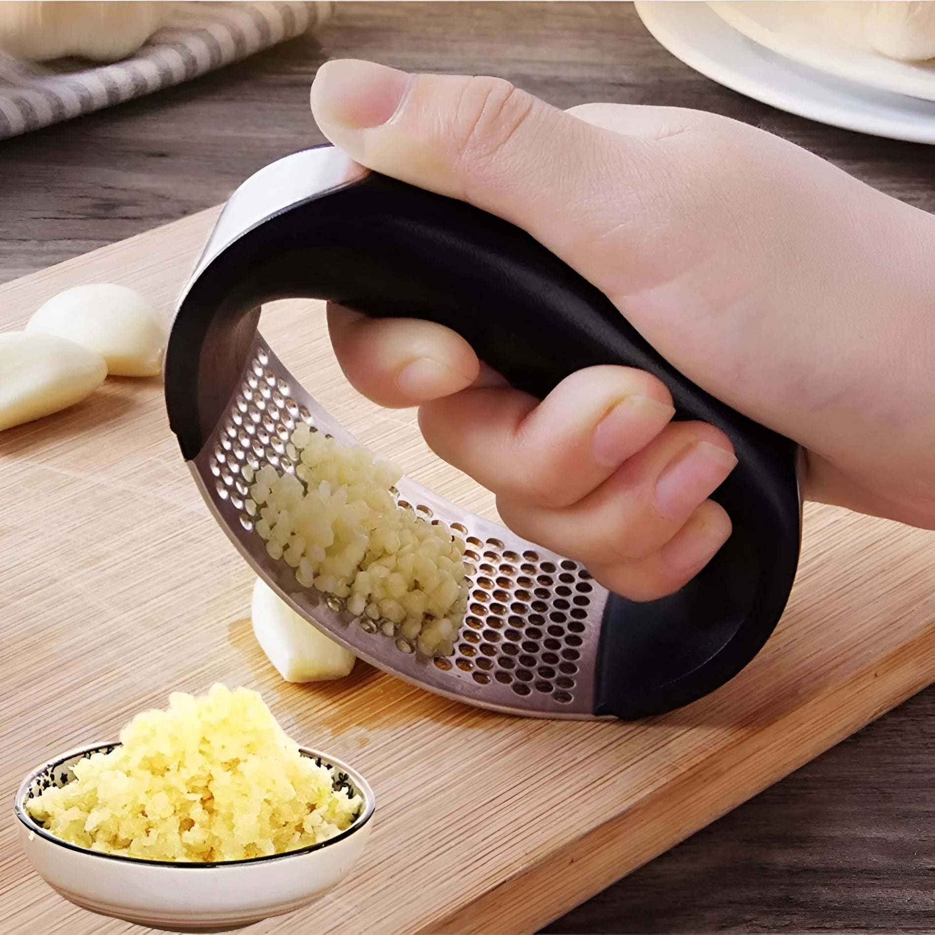 A stainless steel garlic press with a curved design and non-slip ergonomic handle.
