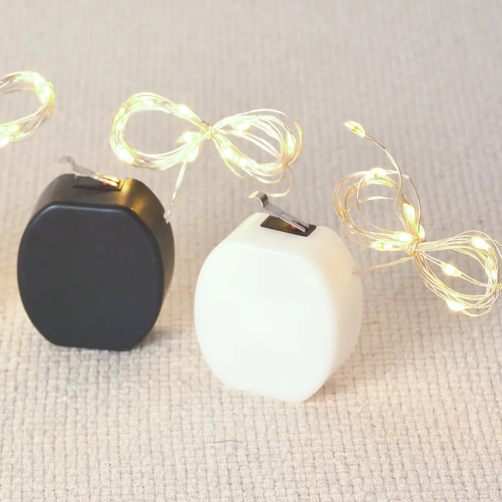 Close-up of a 2 metre long flexible copper wire LED light string with 20 small lights and a white plastic battery box.