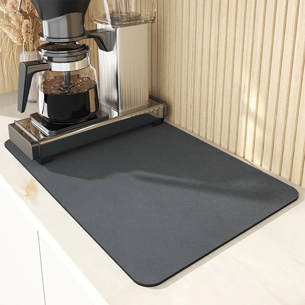 Black square rubber-backed kitchen drying mat on a countertop next to a coffee cup
