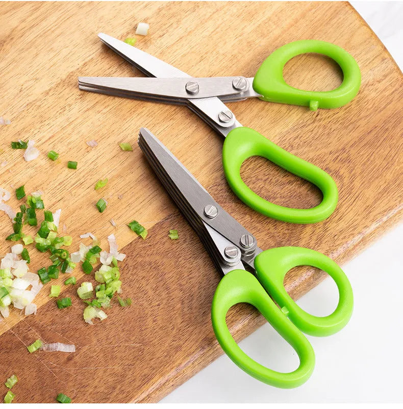 Stainless steel multi-blade kitchen scissors for cutting onions and herbs on a chopping board.