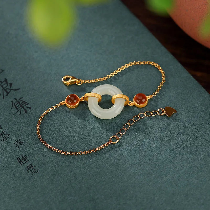 Close-up of a sterling silver bracelet with a gold-plated peace buckle holding inlaid natural Hetian jade.