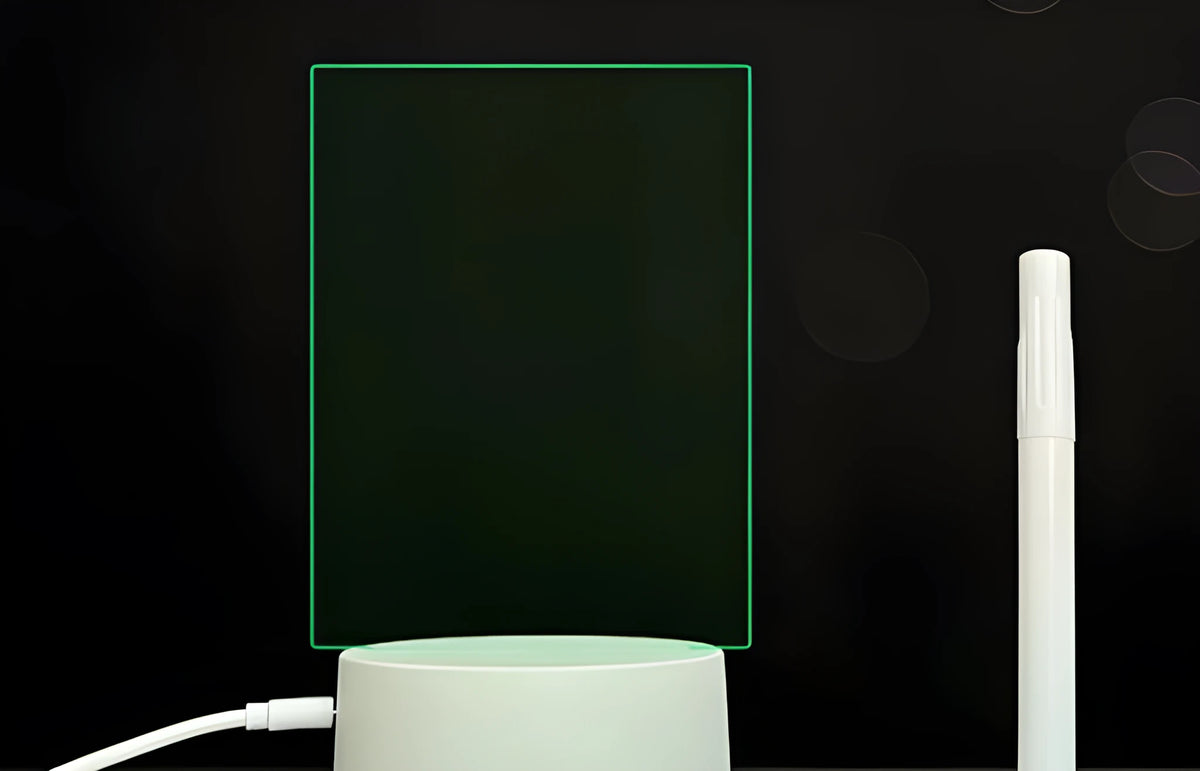 Black 3D acrylic message board lamp with remote control and marker pen on a desk.