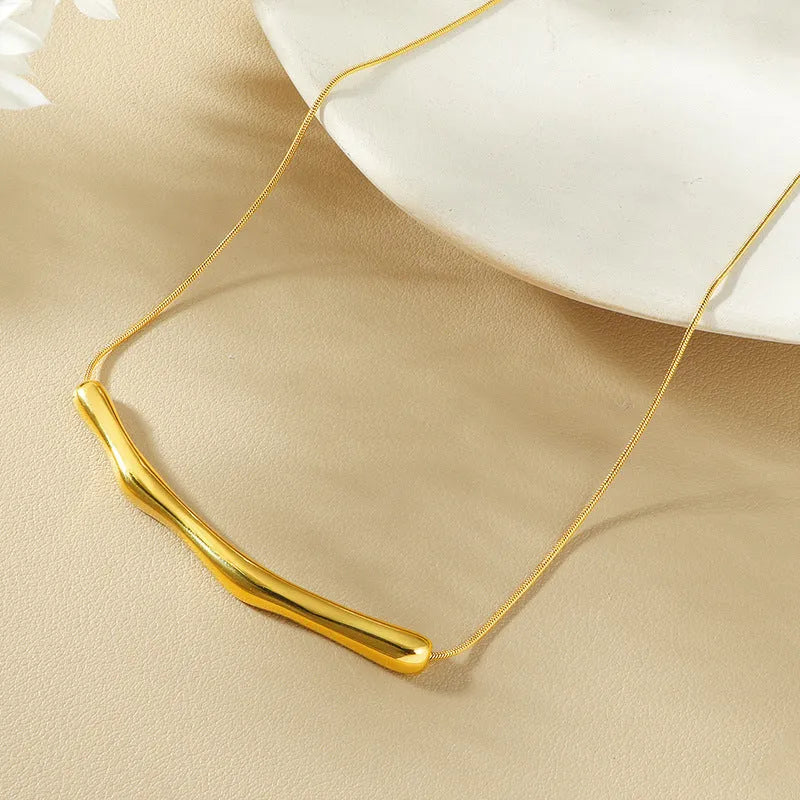 Close-up of a women's titanium steel necklace with an irregular pleated pendant in a gold-tone finish.