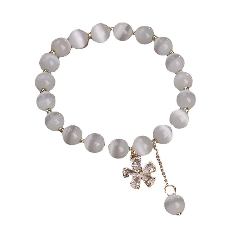 White cat's eye stone single-loop bracelet with a safety buckle, pendant, and small flower tassel decoration.