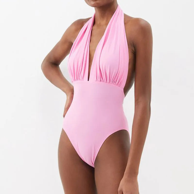 Women's solid colour one-piece swimsuit with deep V halter neck and backless design.