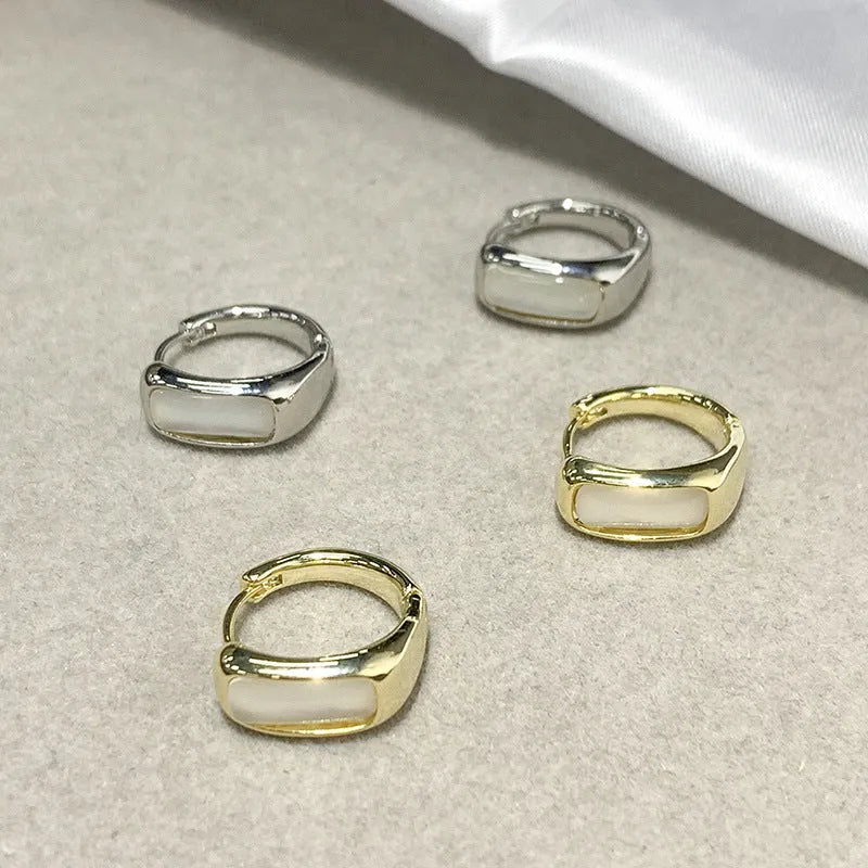 Four pairs of round buckle earrings in gold and silver metal finish on white background