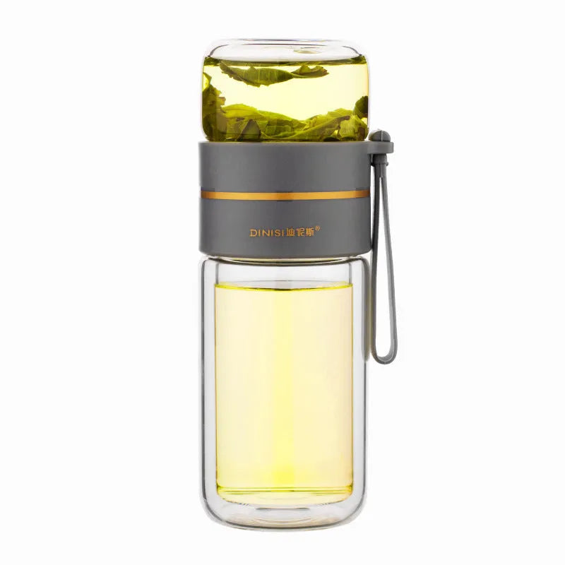 Green double-wall glass water bottle with tea infuser, stainless steel filter, and rope handle on a wooden table.