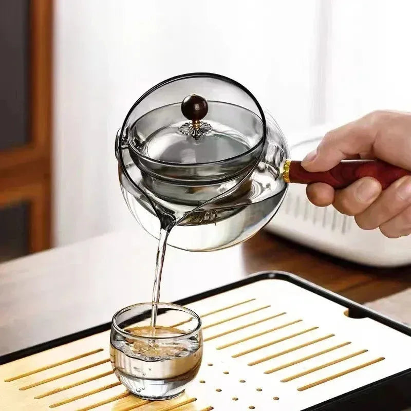 Transparent borosilicate glass teapot with wooden handle and infuser on rotary base