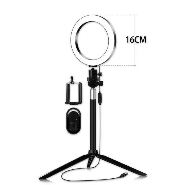 Black 20cm LED ring light kit with tripod, selfie stick, and phone clip on a desk