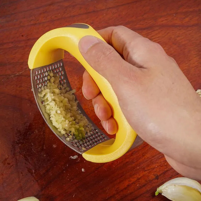 A stainless steel garlic press with a curved design and non-slip ergonomic handle.