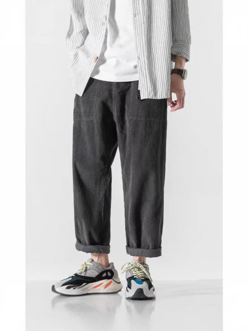 Man wearing loose straight leg tapered trousers in dark grey, showing relaxed fit and straight leg opening.
