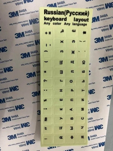 Yellow PVC sheet of glow-in-the-dark keyboard stickers for Arabic, Thai, Hebrew, French, Italian, and German layouts.