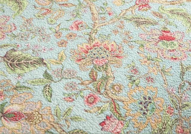Blue American floral and bird patterned cotton quilted bedspread set on a bed, showing the 230x250 cm size