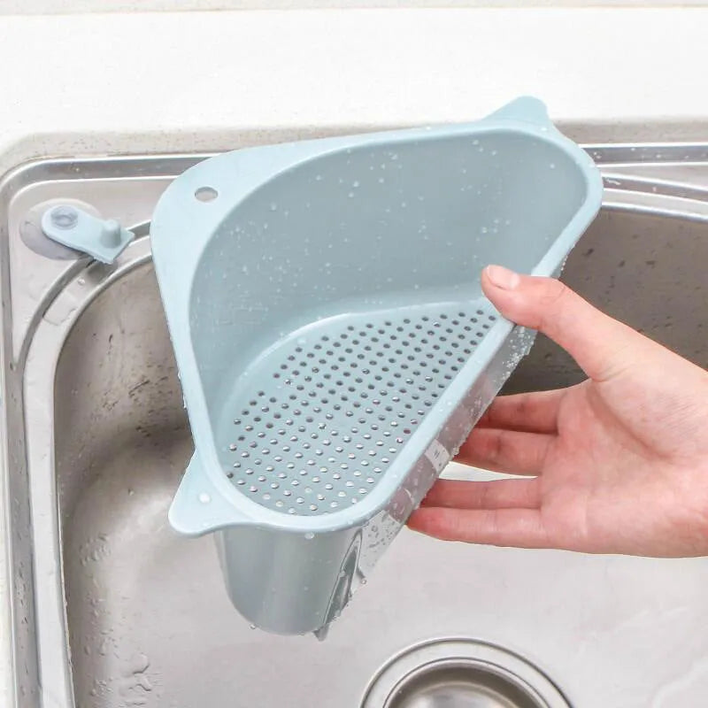 Triangular beige plastic kitchen sink storage rack with suction cup mount holding a sponge.