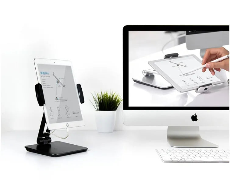 Silver foldable aluminium and ABS phone and tablet stand on a desk, showing 360-degree rotation.