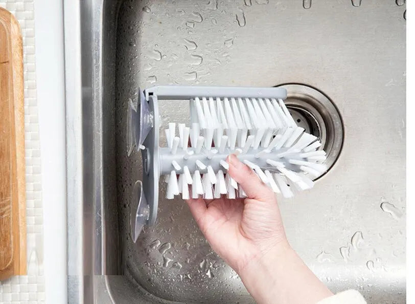 Grey rotating cup brush with two suction cups for wall mounting, shown cleaning a glass