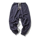 Men's cotton harem joggers in black with drawstring waist, two slant pockets, and tapered ribbed ankle.