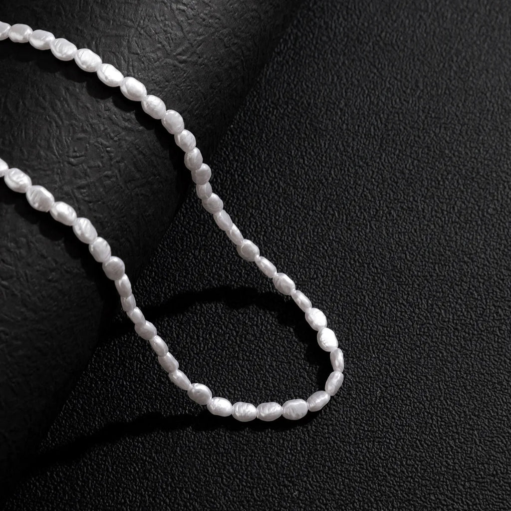 White U-shaped imitation pearl men's necklace with a shellfish pendant on a model.