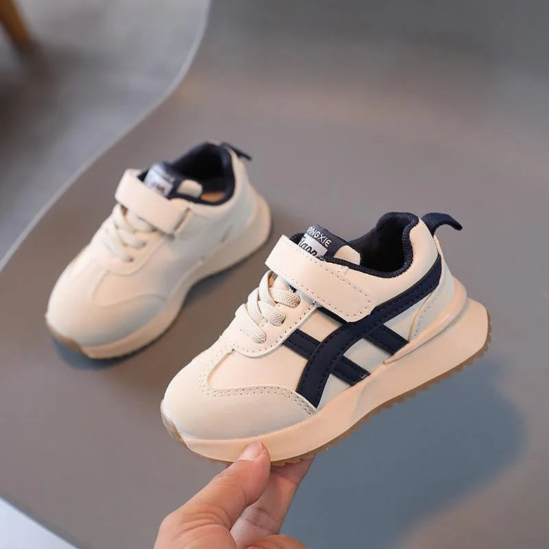 Children's white synthetic leather sneakers with Velcro fastening and textured rubber sole.