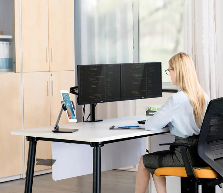 Silver foldable aluminium and ABS phone and tablet stand on a desk, showing 360-degree rotation.