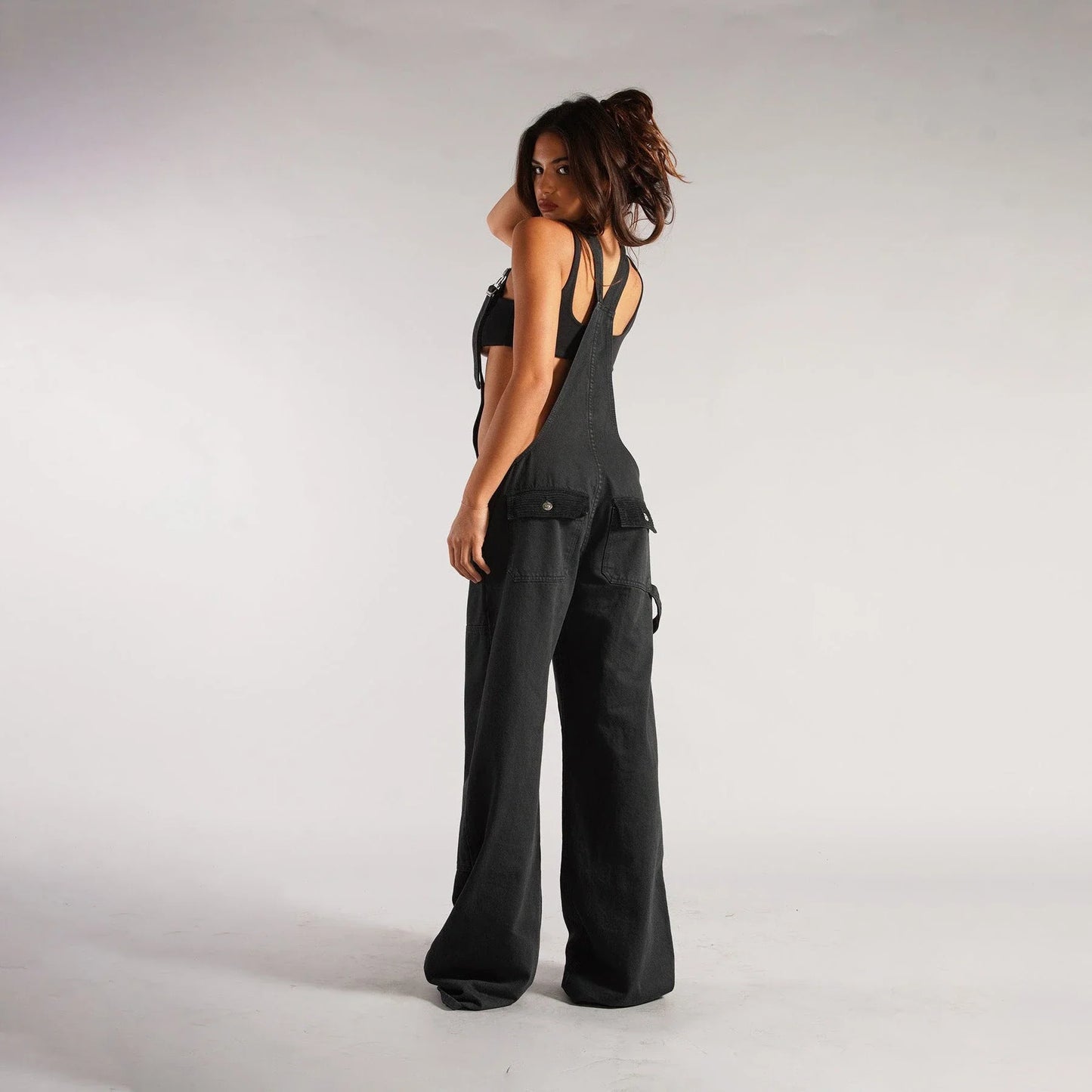 Stylish Y2K-inspired denim suspender jumpsuit with pockets, featuring a relaxed wide-leg silhouette and adjustable straps for a customized fit.