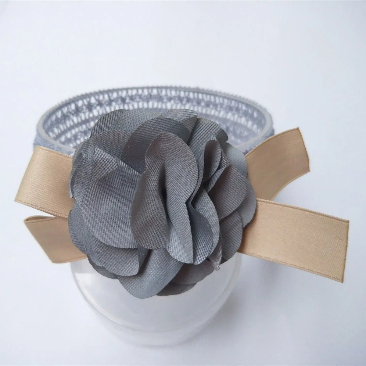 Baby lace headband with fabric flower in grey on a white background