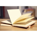 Brown kraft paper sketchbook open to show lay-flat wireless binding and drawing on inner pages.