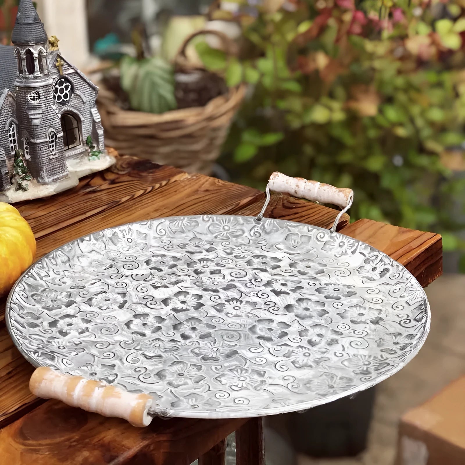 Round wrought iron belt storage tray with raised rim in two sizes on a wooden table.