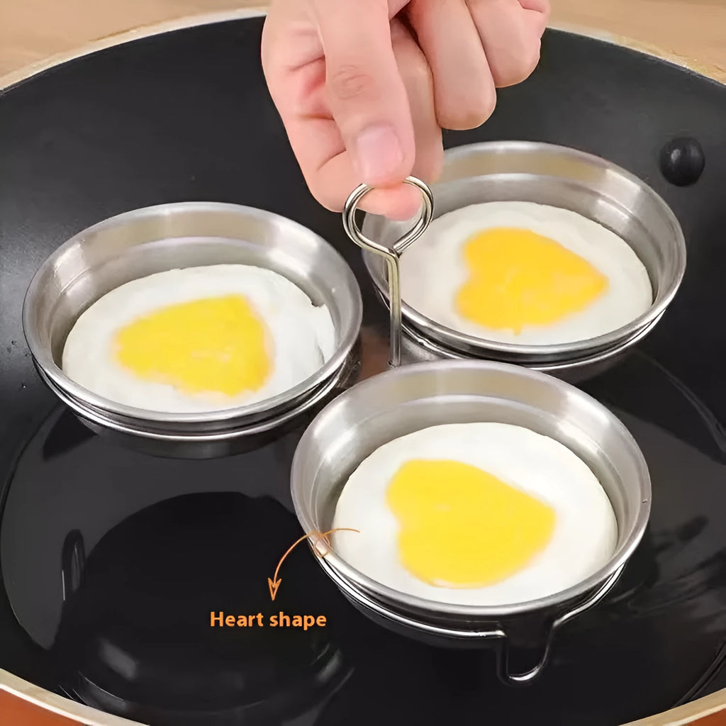 Small stainless steel egg steamer in both round and love-shaped designs on a kitchen counter.